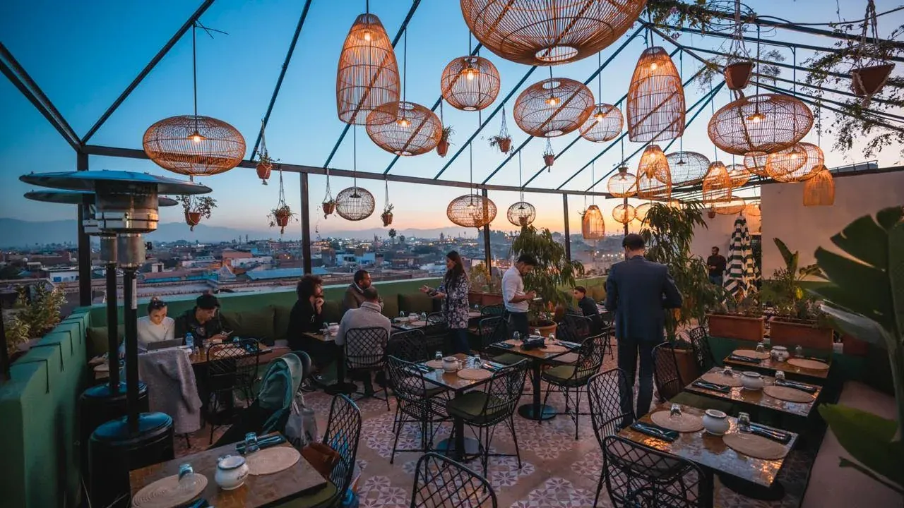 Terrasse du rooftop de L'Mida au coucher du soleil, lanternes en rotin face à la médina