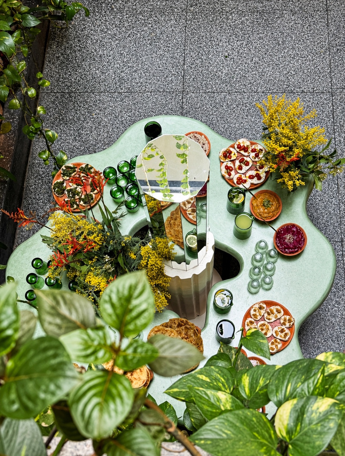 Table ondulée vert d'eau de NBTA garnie de mezze végétaux et de mimosa