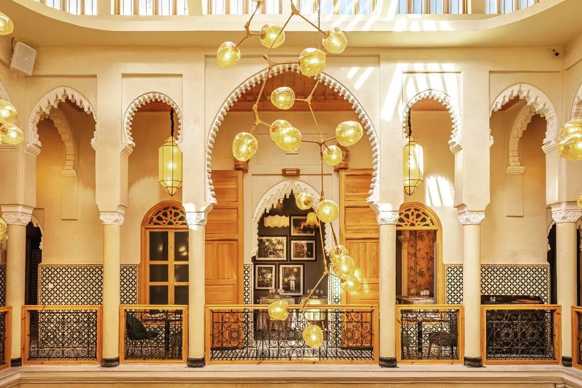 Patio du restaurant Dar Dada dans l'ancienne médina de Casablanca : arcs sculptés, zelliges et suspensions dorées du riad restauré