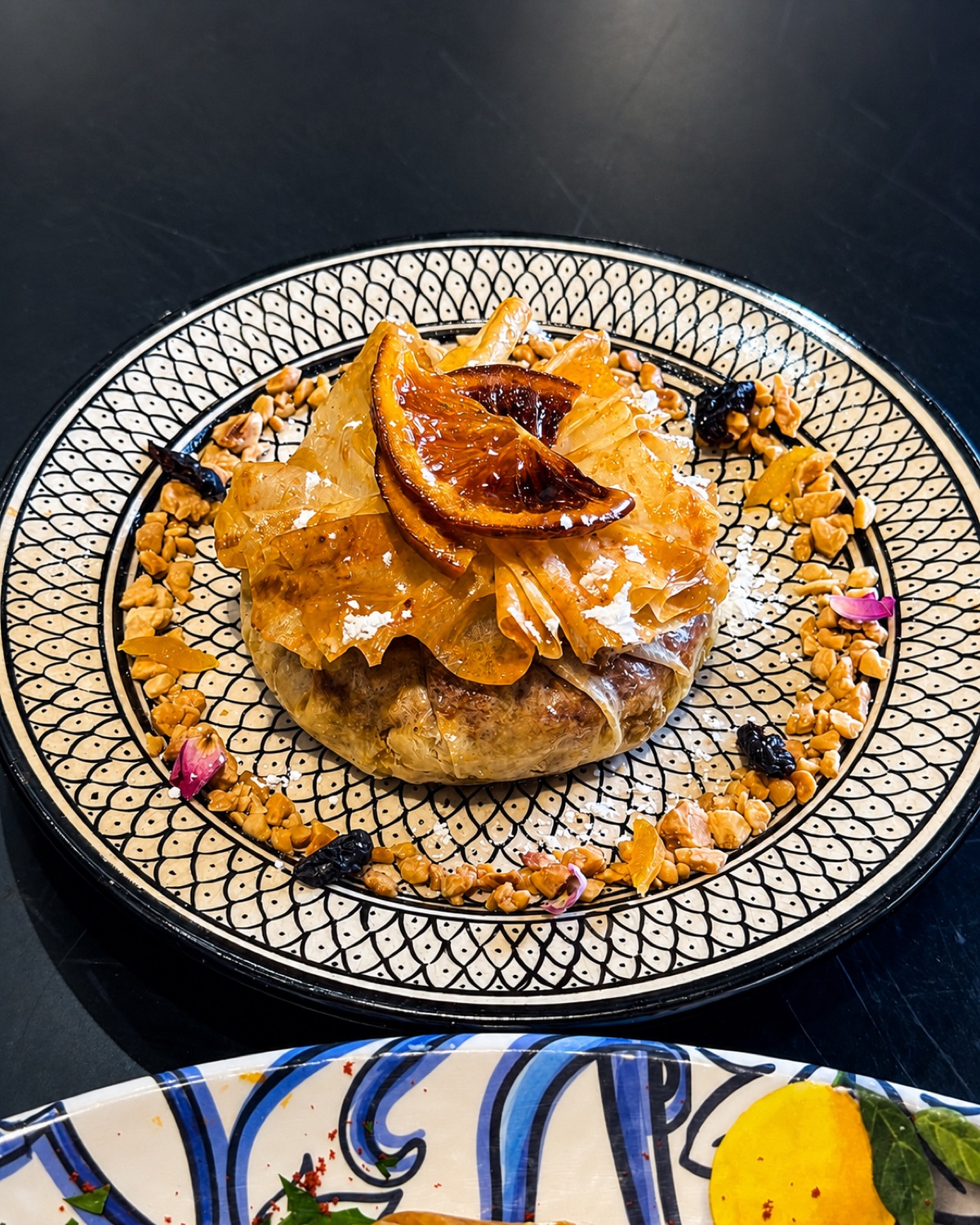 Pastilla dorée servie sur assiette à écailles chez Michwate Fès