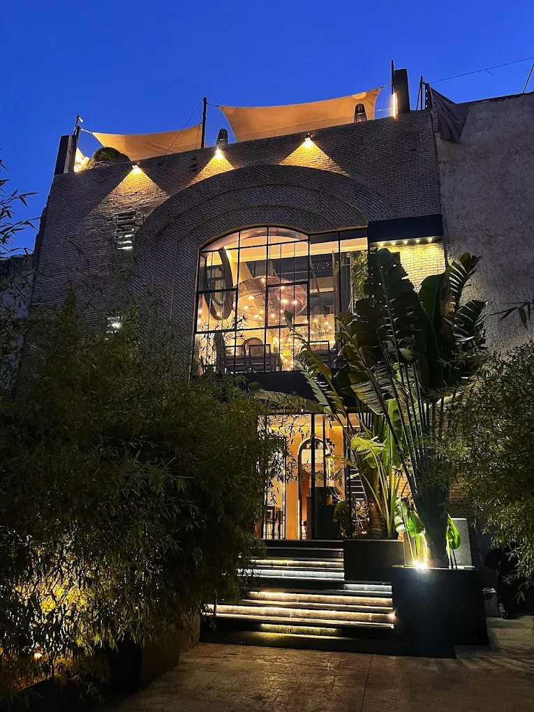 Façade en arche du restaurant Ishq à Fès, verrière illuminée au crépuscule et rooftop aux voiles tendues