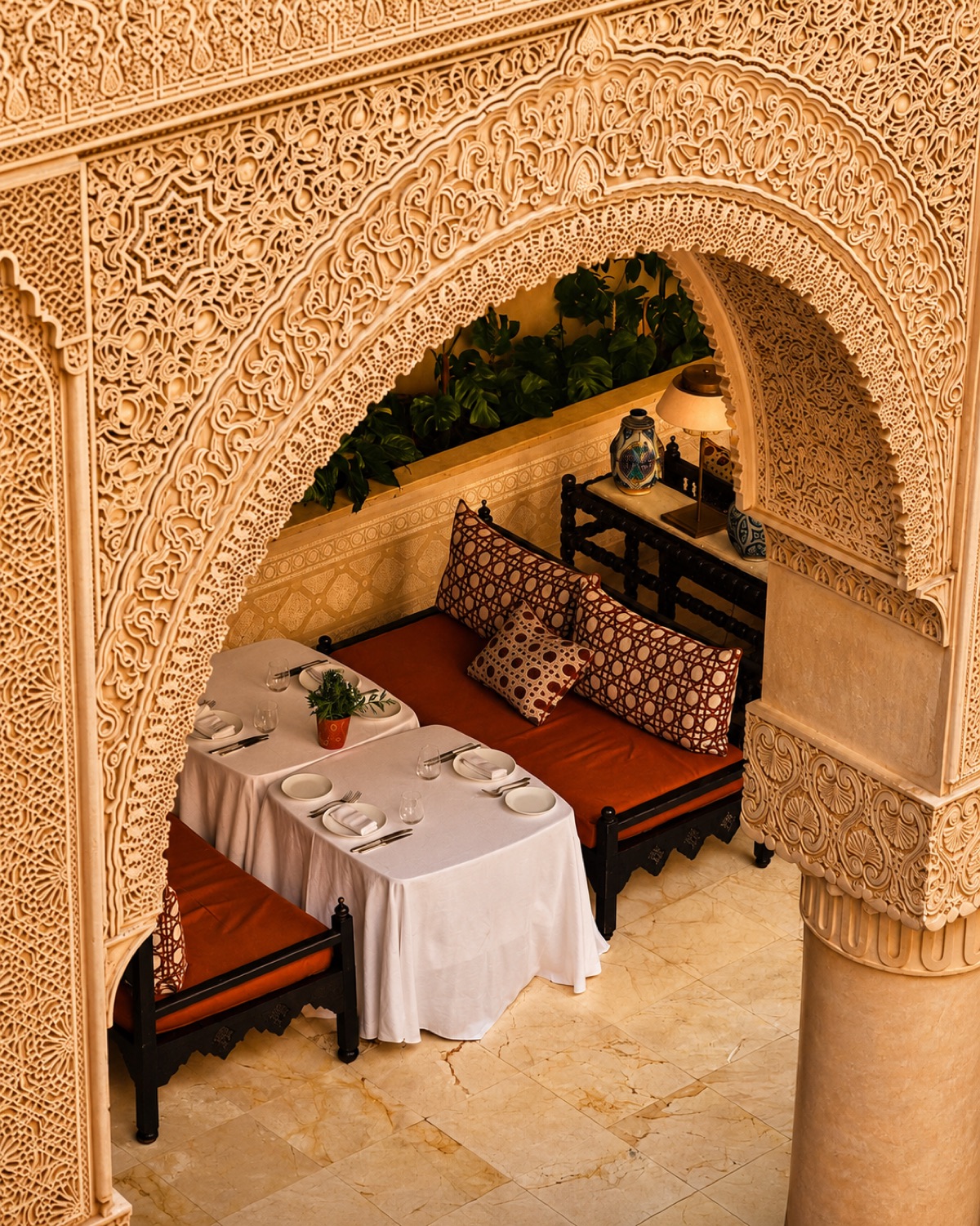 Arche en gebs sculpté et banquettes rouges du Riad Fès